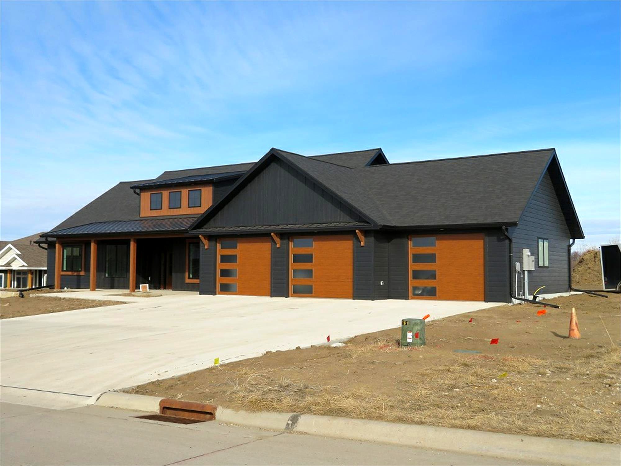 Charcoal board-and-batten home with cedar-tone garage doors, built by J&J